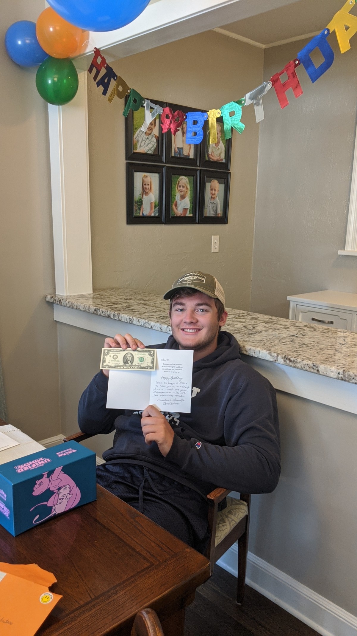 Smiling teenage boy holding a birthday card and a two-dollar bill.