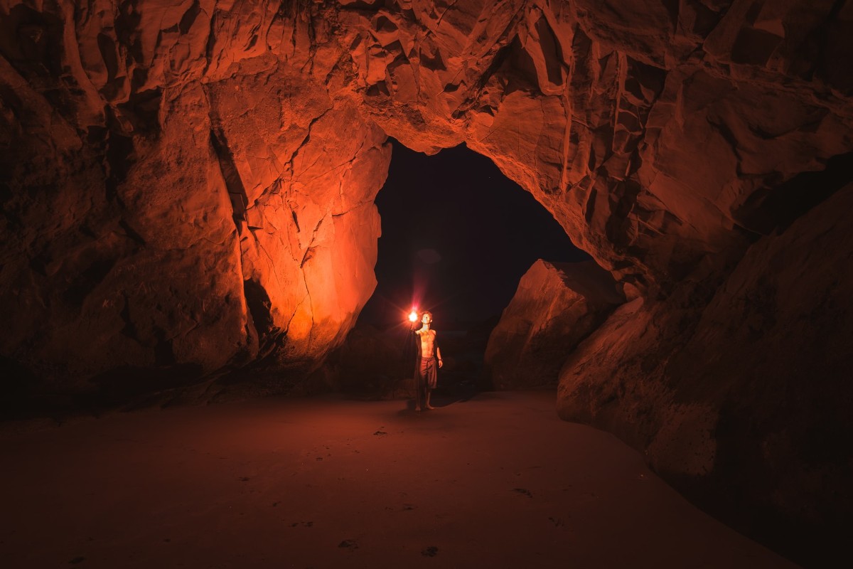 Person in a cave holding a light.